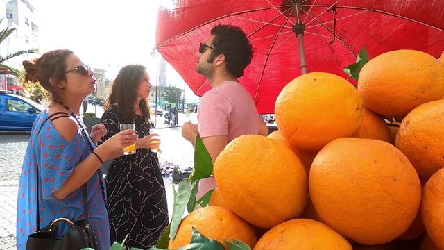 Tourists drinking freshly squeezed orange juice at a Moroccan street stall