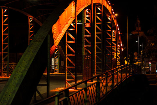 Fototapeta An old steel bridge in various colors, during the night