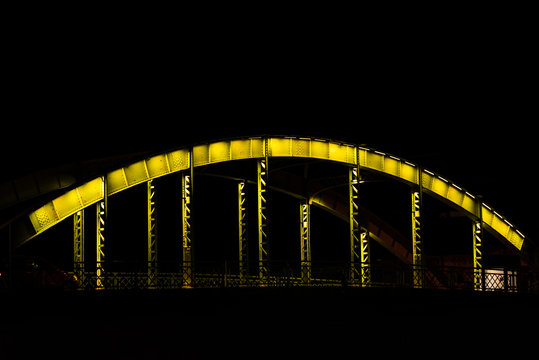 Fototapeta An old steel bridge in various colors, during the night