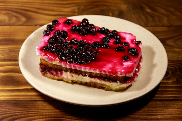 Tasty cheesecake with black currant on wooden table