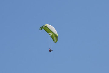 Flying green skydiver with blue sky in the background.