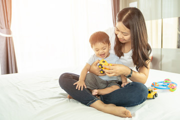 Happy loving family. Mother playing with her baby in the bedroom. Pretty woman holding a newborn baby in her arms, Mother with child playing educational toys 