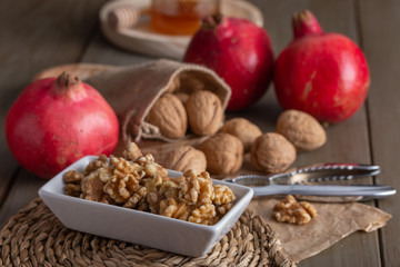 Autumnal still life with walnuts, honey and pomegranates on a kitchen table with a nutcracker