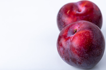 Two purple plums isolated on a white background