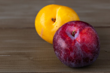 Yellow and purple plums on a wooden table