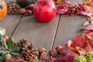 Autumnal composition with pomegranate, gourds, pine cones and berries on a kitchen table 