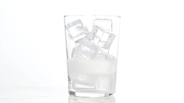 Vertiendo agua con gas en un vaso con hielos