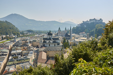Obraz premium Landscape view of the city of Salzburg in Austria with a cathedral and a castle in the background.