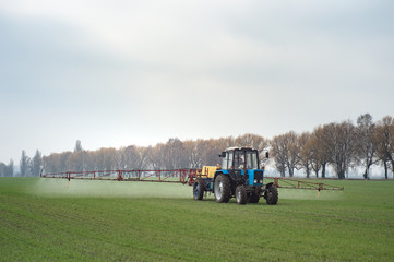 wheat field tractor spraying agrochemical or agrichemical over young grain field in most cases agrichemical refers to pesticides like insecticides herbicides fungicides and nematicides