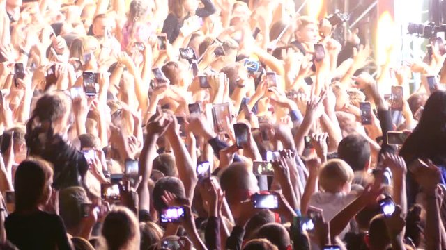 Fans use gadgets during the festival. Many people's hands record video. Festival of electronic music.