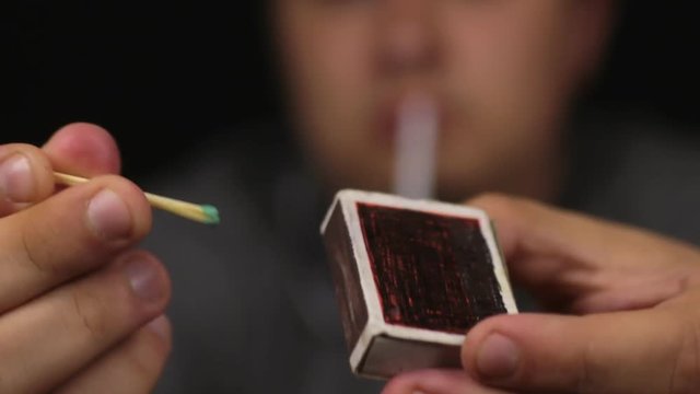 Close-up, man set fire to a wooden match. Focus on the match.