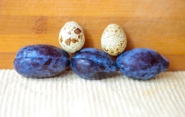 Blue plums and quail eggs stand in a row