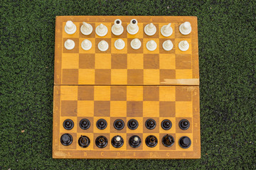 symmetry yellow wooden chess desk frame from above and black and white figure in start positions before game