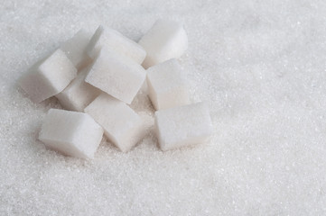 Sugar cubes on white sugar background