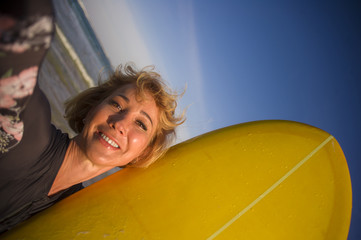 Obraz premium young attractive and happy blonde surfer woman in swimsuit holding surf board in the beach taking self portrait selfie picture smiling cheerful enjoying holidays