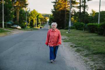 An elderly woman strolls through the village.