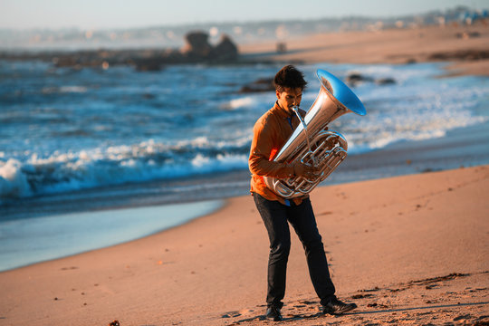 Musician instrumentalist playing the Tuba on the sea coast.