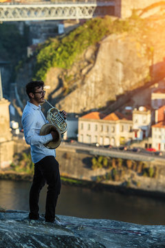 Man musician with trumpet opposite Dom Luis I bridge in Porto, Portugal.
