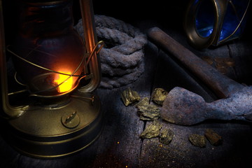 Lantern, axe, gold mining and treasure hood concept.Wood background