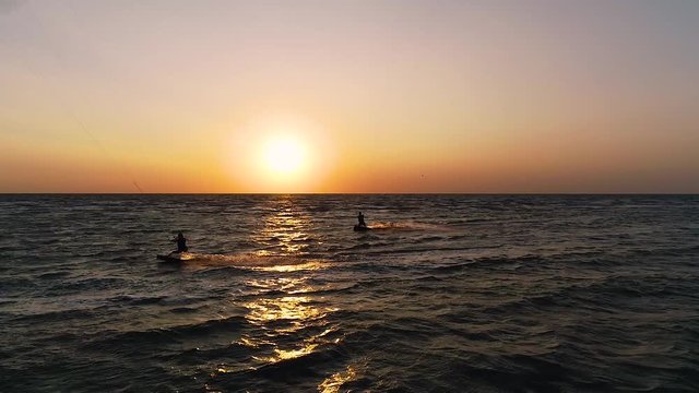 Dron flies in the air and takes off a group of kiteurs that control training kites in the sea at dawn