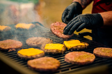  guy is cooking a cutlet with cheese for burgers on an open fire © smirart
