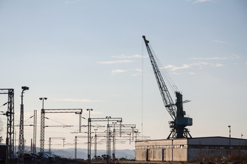Industrial landscape at sunst, with an electrified railway line and its tracks, next to a heavy...