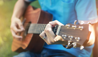 The man is playing guitar in the garden, Close-up male hand playing on acoustic guitar outdoor with...