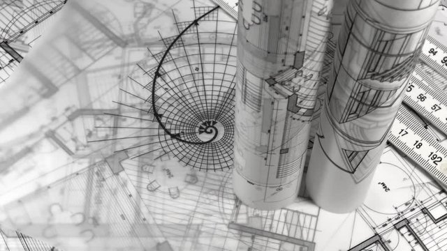 Blueprints - rolls of architectural drawings, yardstick - folding ruler and drawing of the golden section smoothly rotate on the surface of the architectural drawings