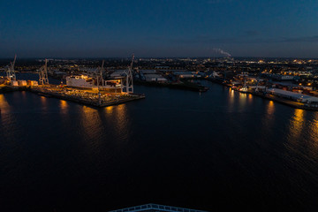 Fototapeta premium Aerial view of big cargo ship loading with containers at port of Hamburg, Germany. Beautiful sunset.