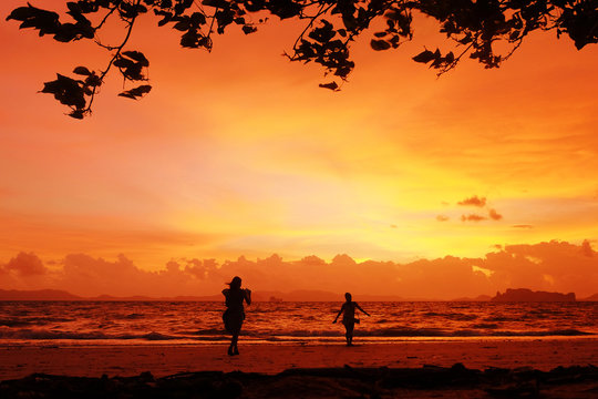 Photoshoot on sunset. Silhouettes of girls posing on the beach with crazy red sky on the background. Krabi, Thailand.