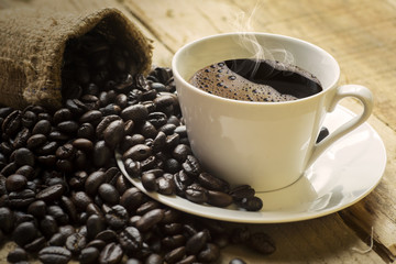 Cup of hot coffee with smoke and coffee beans