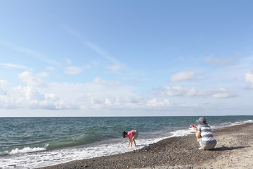 海辺で遊ぶ親子　母と娘　青い海と青空