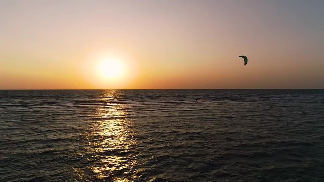 Panoramic views of sea during sunset, a lonely man controls a training kite