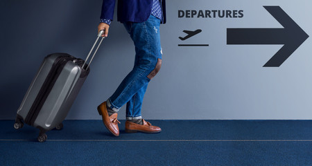 Traveling Concept, Young Traveler Walking with Suitcase and Follow the Departures Sign in the Airport