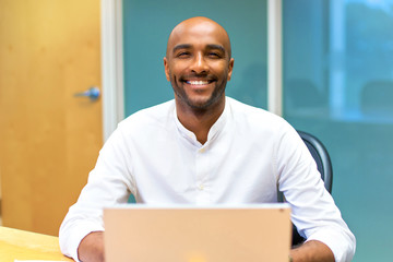 Happy young afro american businessman in the office with his laptop