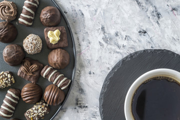 A cup of coffee and chocolates on a plate.