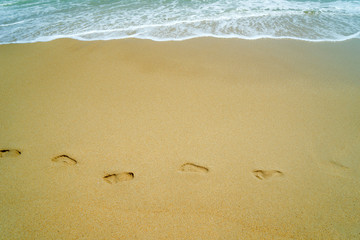  woman relaxing walking on sand beach leaving footprints in the sand.