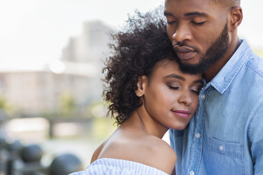 Tender black couple hugging with closed eyes