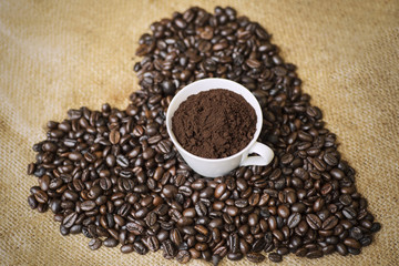 Ground coffee in a cup with coffee beans