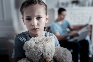 Crying kid. Unhappy upset kid looking at you while holding a teady bear
