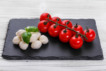 Mozzarella tomatoes and basil on a wooden rustic background