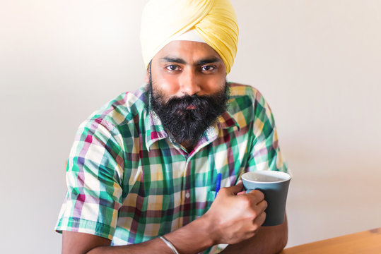 Indian with turban holding a cup of coffee - Powered by Adobe