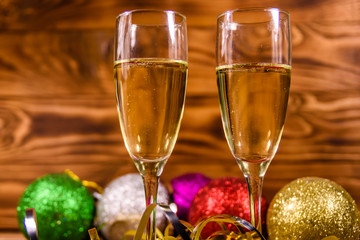 Two wineglasses with champagne and different christmas decorations on wooden table