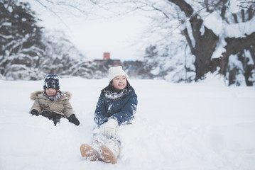 Fototapeta na wymiar Cute Asian children playing on snow in the park together , Aomori Japan