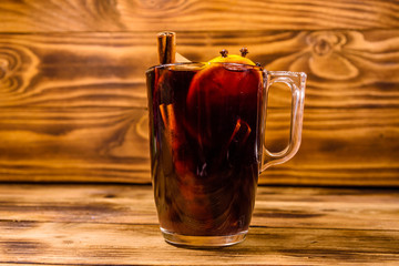 Cup of mulled wine with cinnamon on wooden table