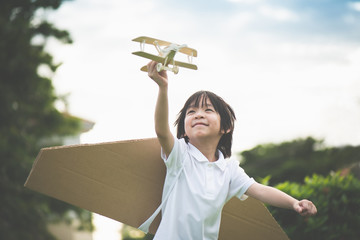 Cute Asian child playing wooden airplane in the park outdoors