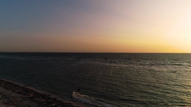 Top view, male kiter floating near shore at sunset. Slow motion