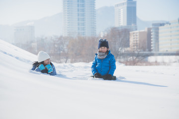 Asian children lying on snow together
