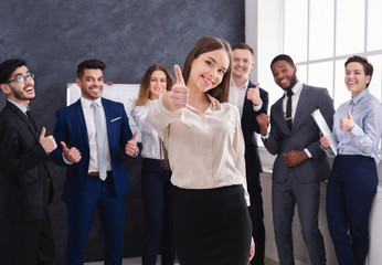 Attractive businesswoman showing thumb up in office