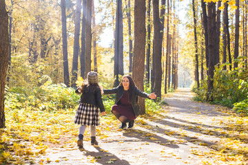 Fototapeta premium Motherhood, family and seasons concept - happy family of mother and daughter playing in the autumn park